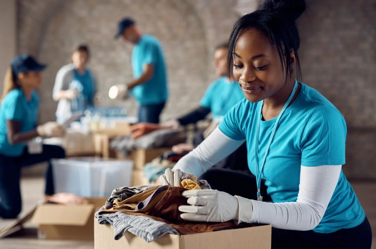 A volunteer smiles as she gently packs folded clothing into a box
